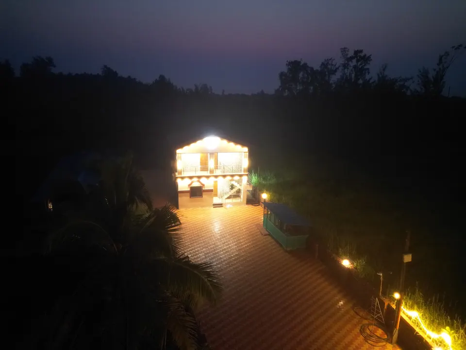 Aerial view of the villa lit up at night, with the tiled courtyard and trees around it
