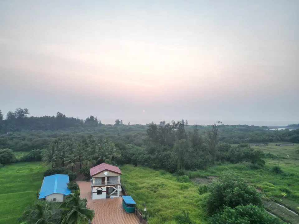 Aerial view at dusk of the villa and its tiled approach, with green fields and trees all around