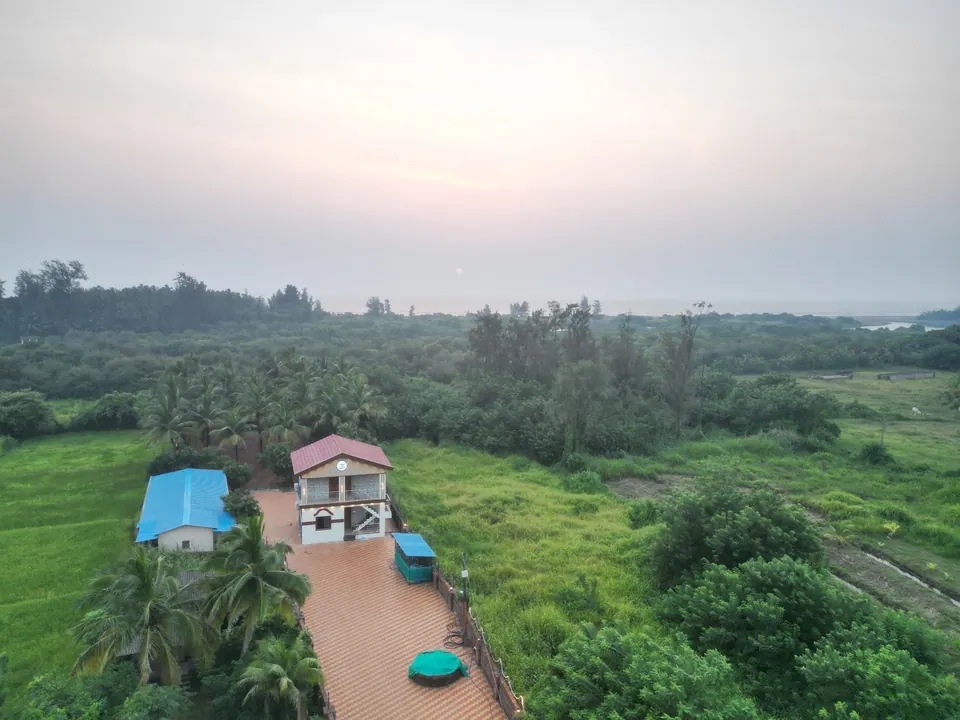Aerial view of the villa and the tiled path leading to it, with fields and trees on both sides