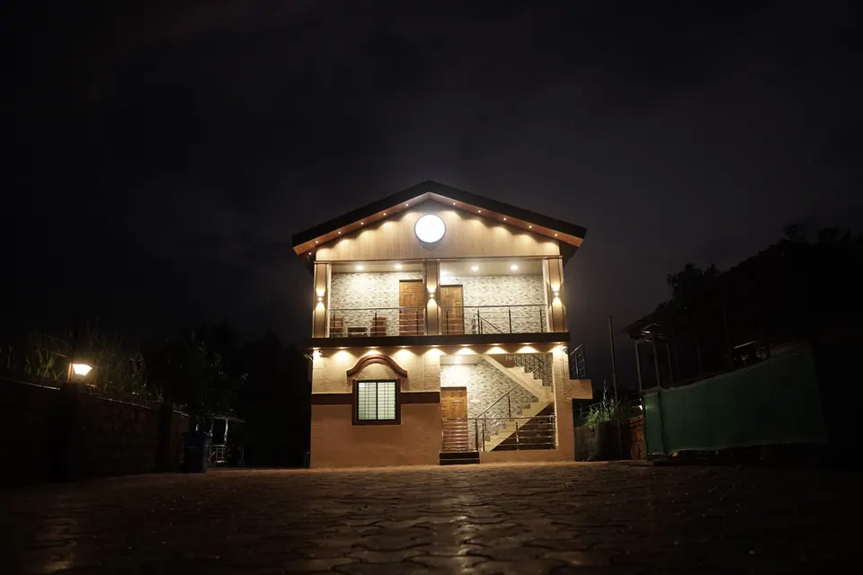 Two-storey villa lit up at night, with warm lights along the roofline and the outside staircase