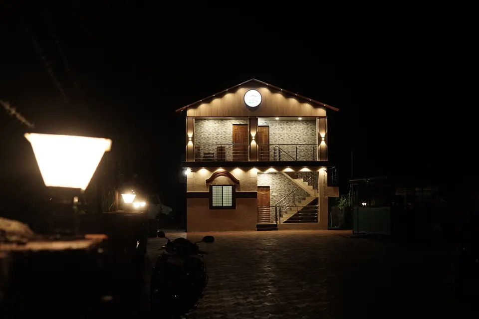 Two-storey villa lit up at night, seen past a glowing courtyard lamp