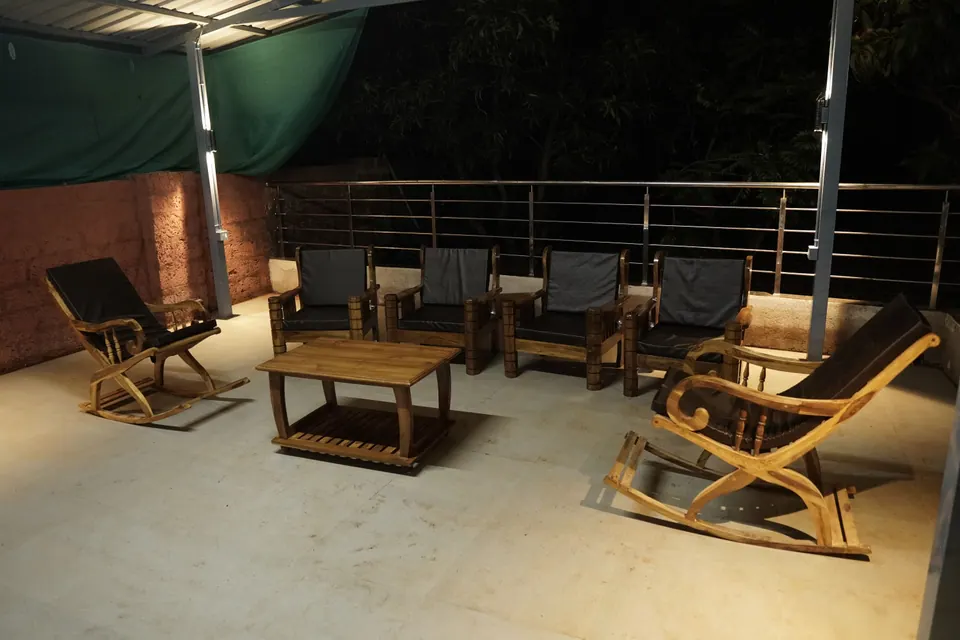 Terrace seating with rocking chairs, armchairs and a wooden coffee table under lights at night