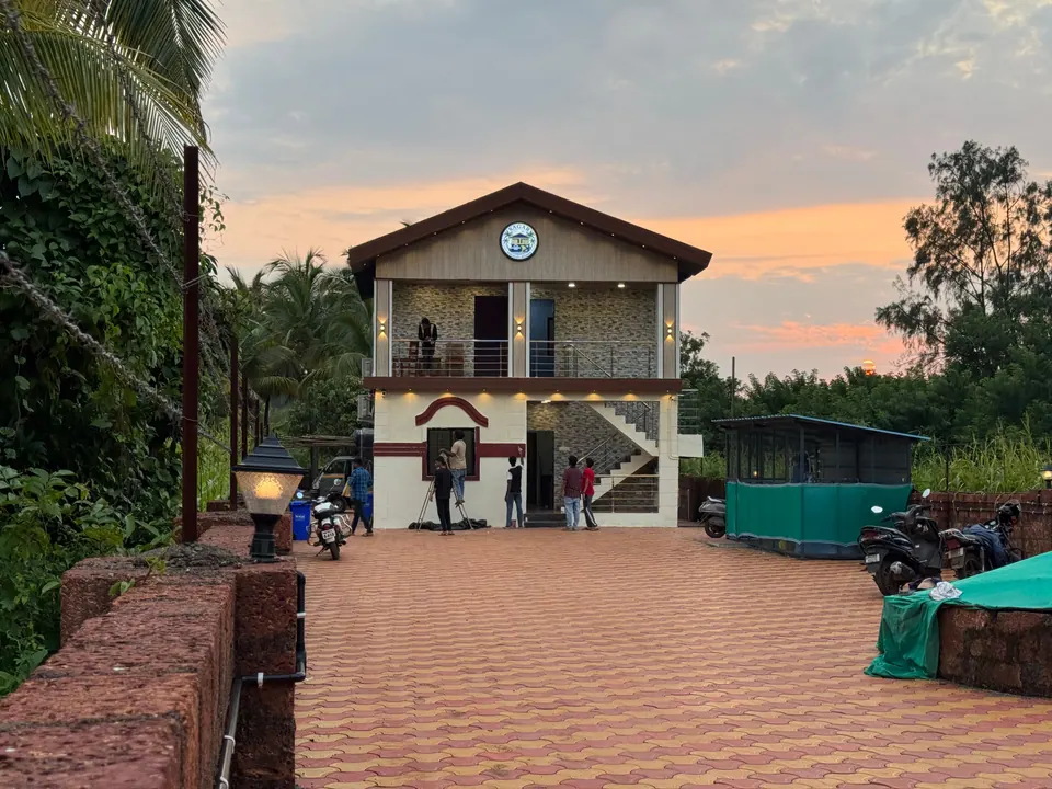 Two-storey villa with a pitched roof and an outside staircase, with a tiled courtyard in front, at sunset