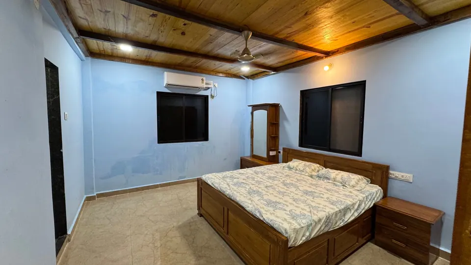 Bedroom with blue walls, a wooden bed, an air conditioner and a wood-panelled ceiling