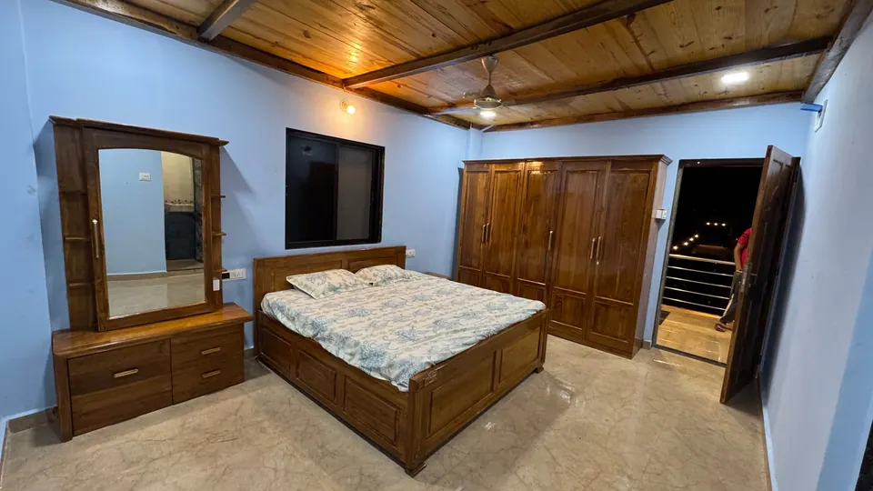 Bedroom with blue walls, a wooden bed, a dressing table with a mirror and a large wooden wardrobe