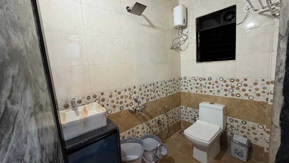 Bathroom with patterned wall tiles, a wash basin, a toilet and a water heater