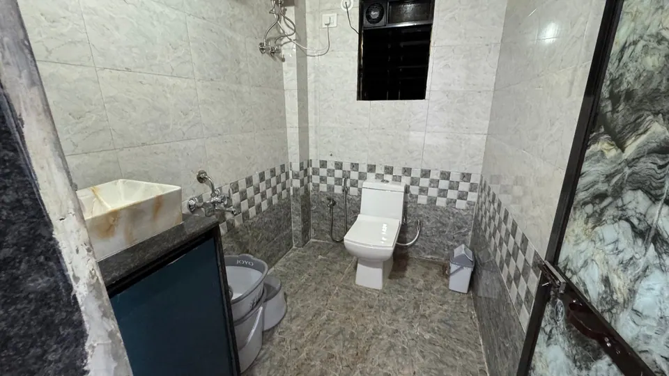 Bathroom with grey checked wall tiles, a wash basin and a toilet