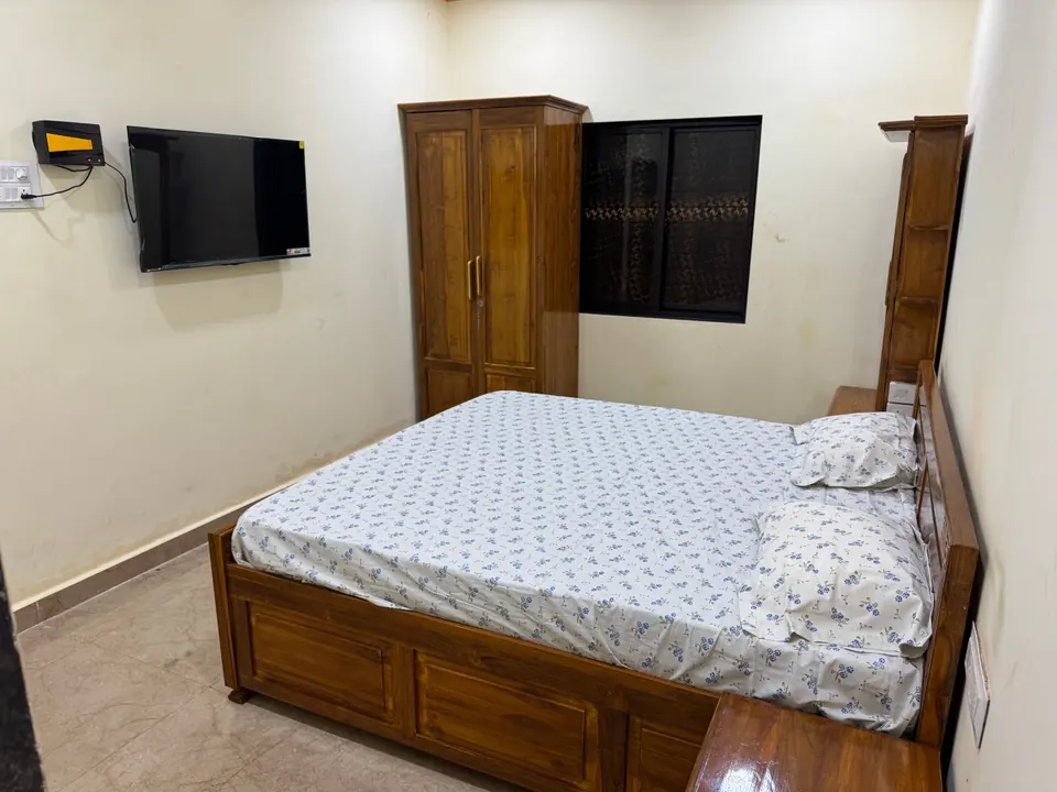 Bedroom with cream walls, a wooden bed, a wall-mounted TV and a wooden wardrobe
