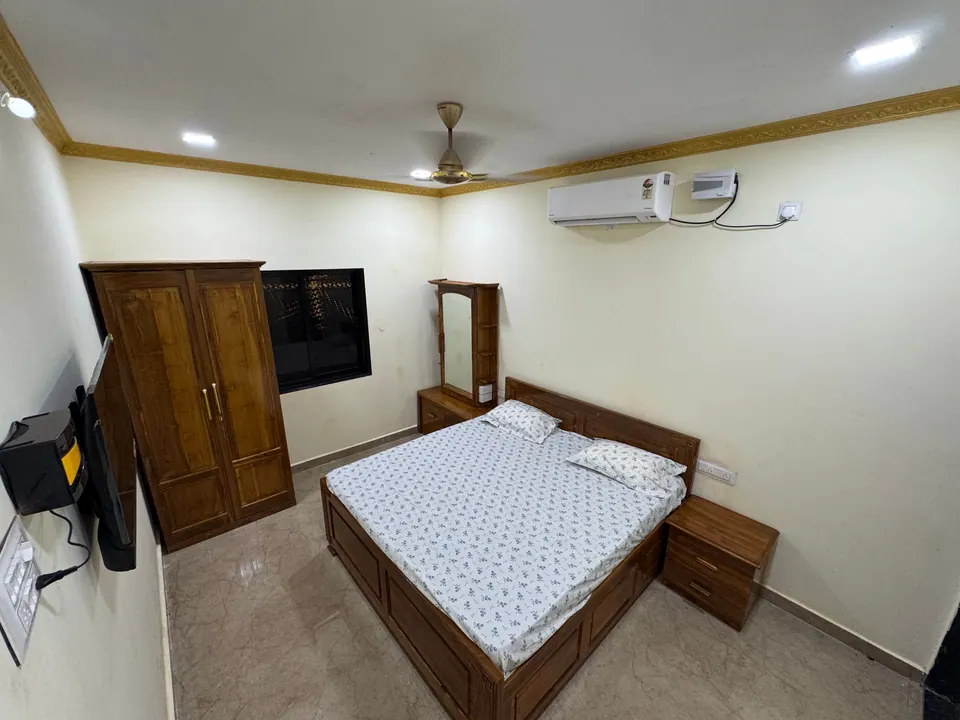 Cream-walled bedroom with a wooden bed, a wardrobe, a wall-mounted TV and an air conditioner